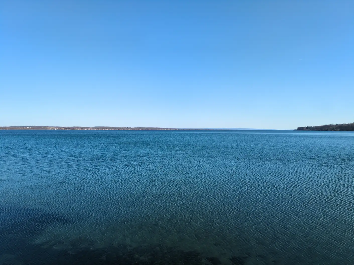 A clear blue lake in the late afternoon, with darker texture in the water near the camera.
