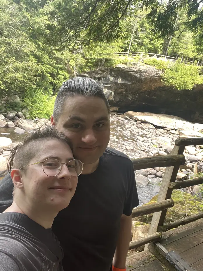 My partner and me, with a walkway handrail and a marble cave entrance visible in the background